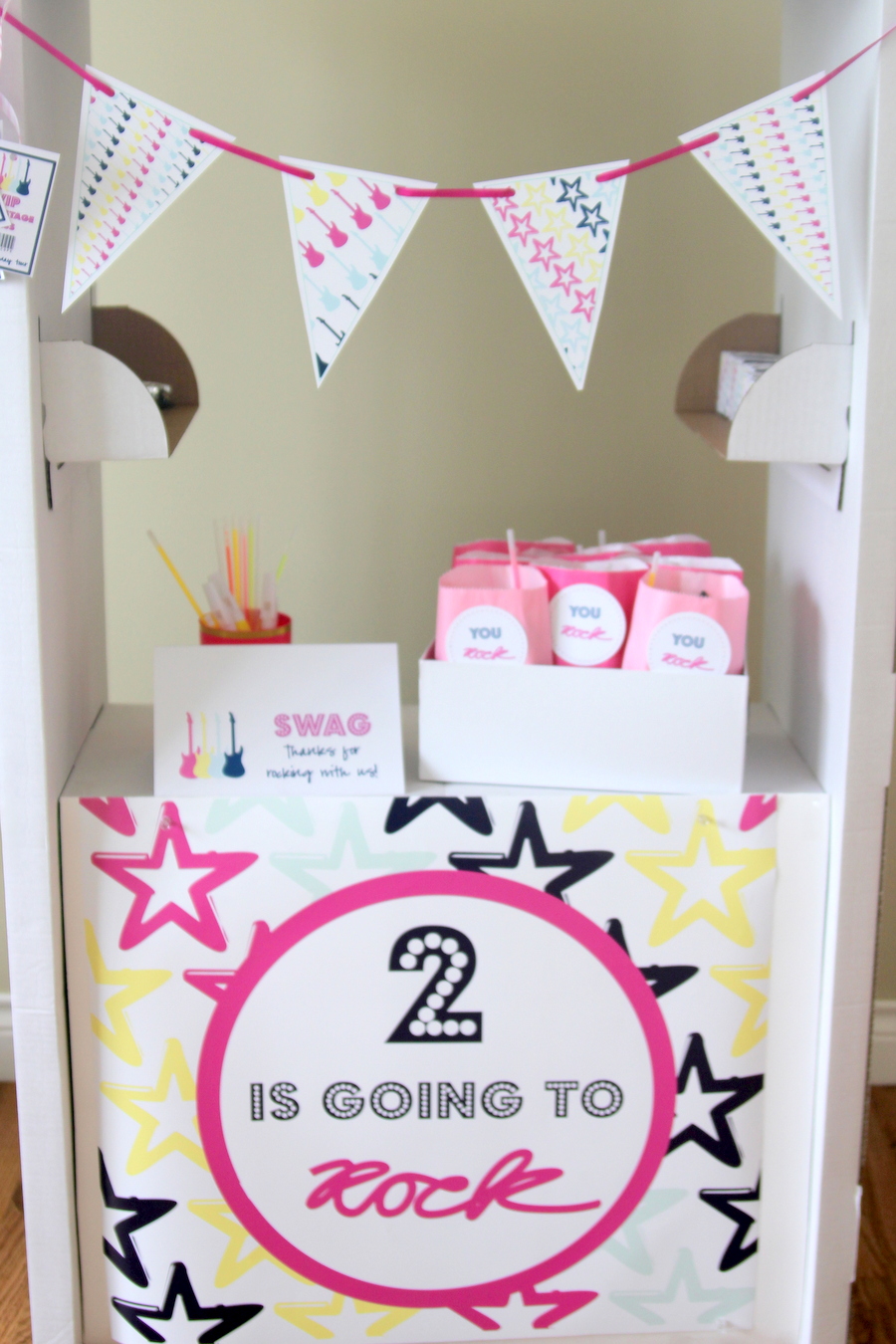 Time to party like a rock star! This sweet rock star birthday party includes all sorts of party ideas- like this cute swag booth made from a $15 IKEA cardboard market!